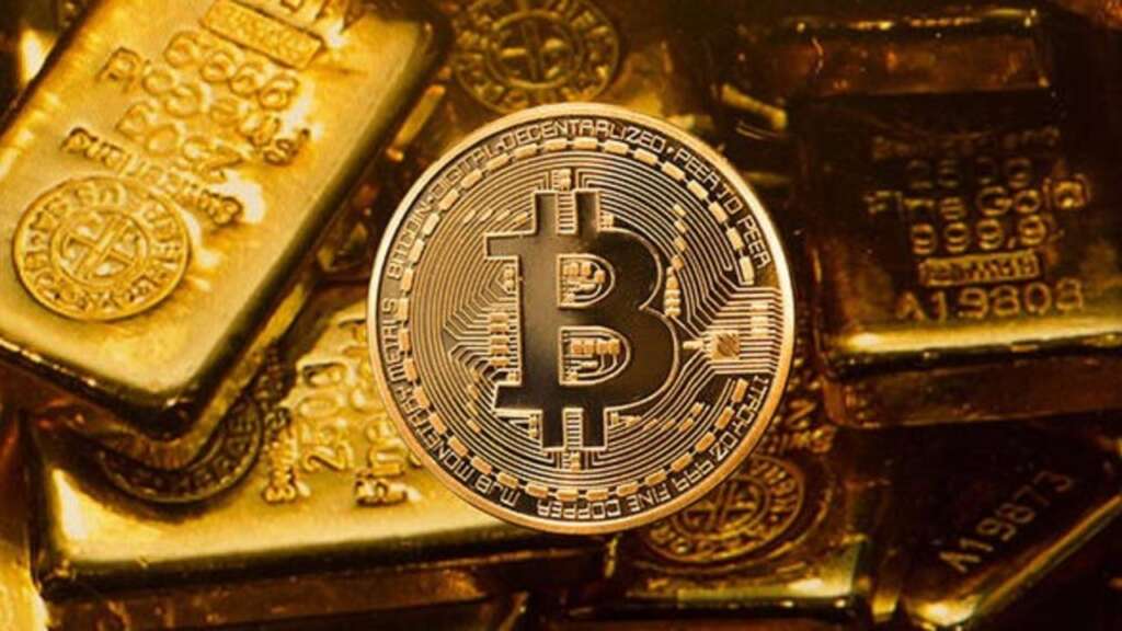 Una moneta di Bitcoin tra alcuni lingotti d'oro
