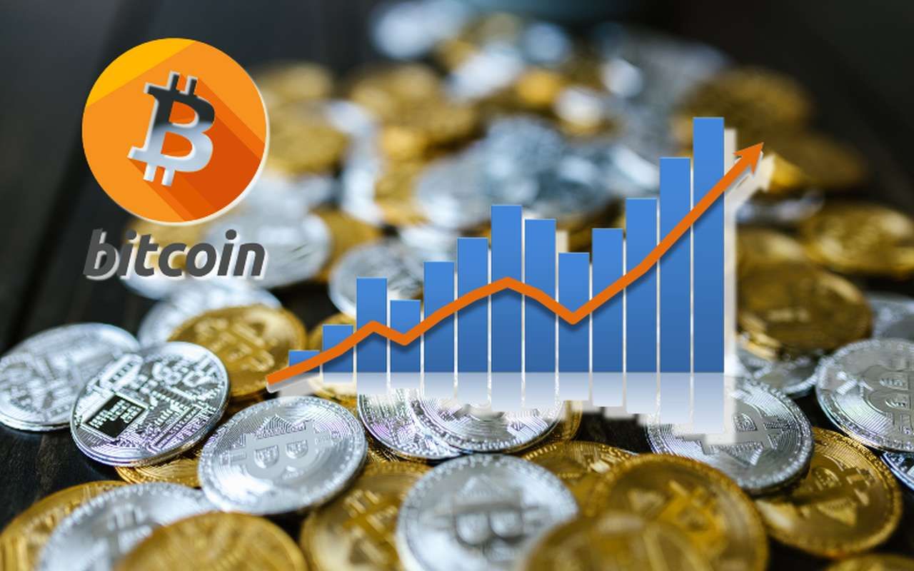 logo e scritta Bitcoin, un grafico a candele, e sullo sfondo tante monete di Bitcoin color oro e argento