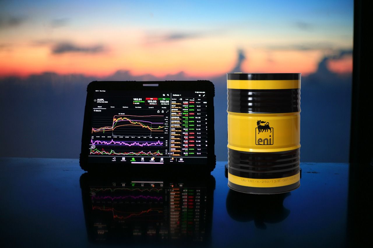 tablet con grafico di trading e barile di petrolio con marchio Eni