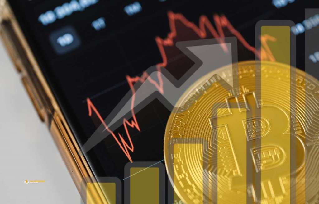 Una moneta di Bitcoin sullo schermo di uno smartphone con dei grafici finanziari