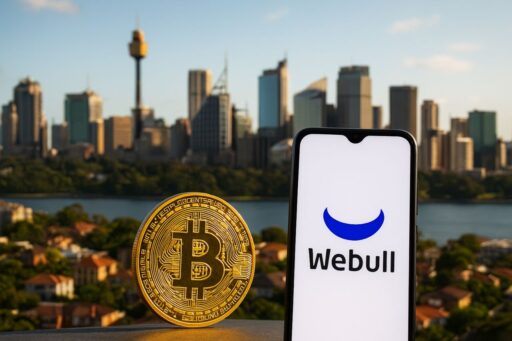 Una moneta di Bitcoin e un dispositivo mobile con la scritta Webull sullo schermo. Sullo sfondo una metropoli australiana
